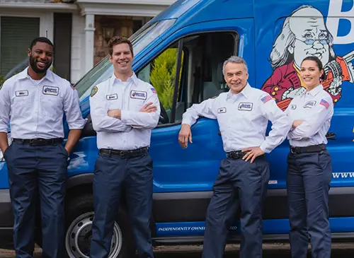 Benjamin Franklin Plumbing team members Mike, James, Jose, and Layla standing in front of a blue company van in Pompano Beach.